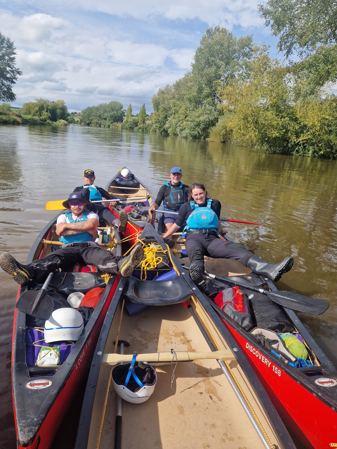 Outdoor instructor training students canoeing together on a calm river during paddlesports expedition. 