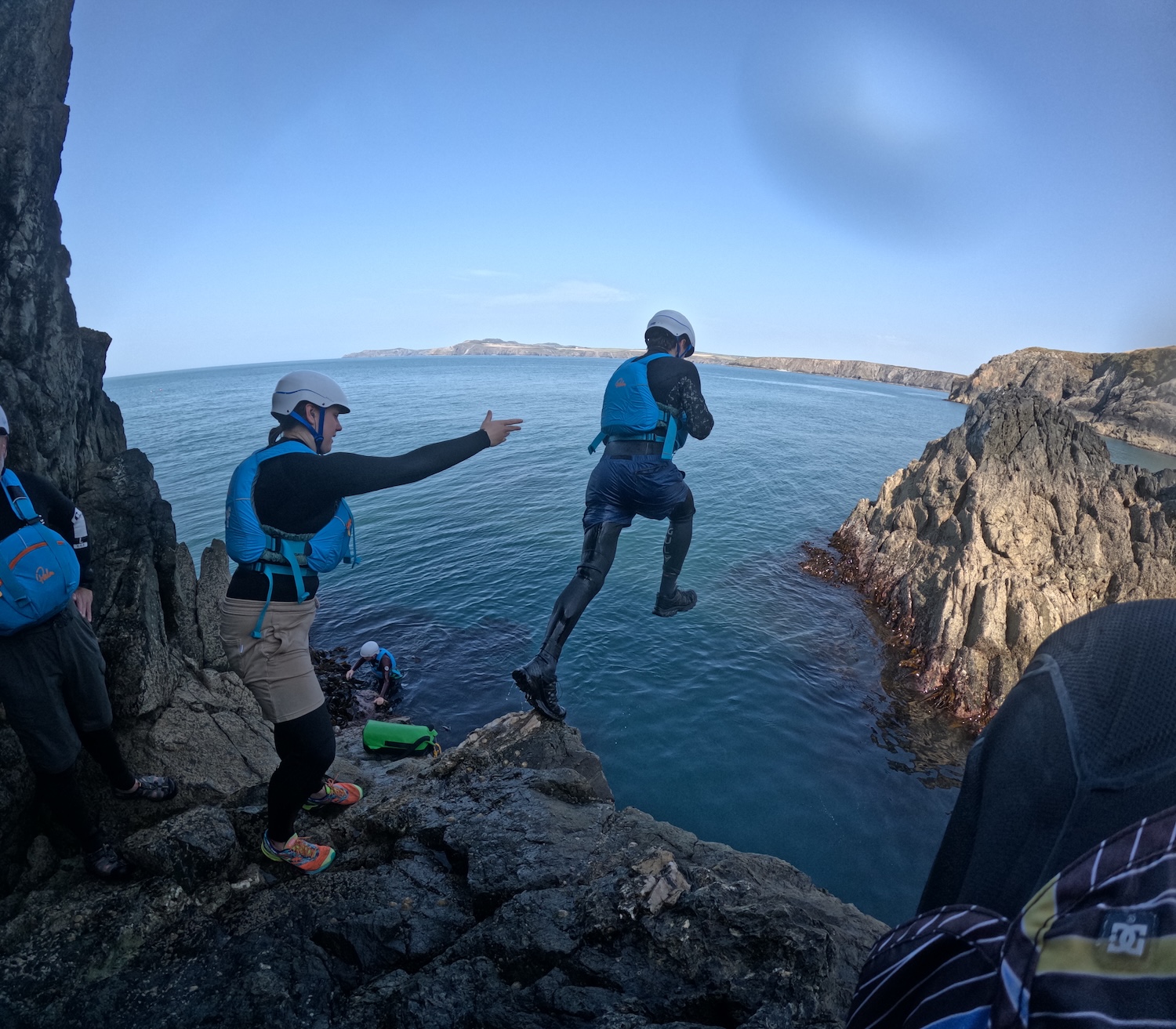Outdoor instructor training students coasteering, jumping into the sea under instructor supervision.