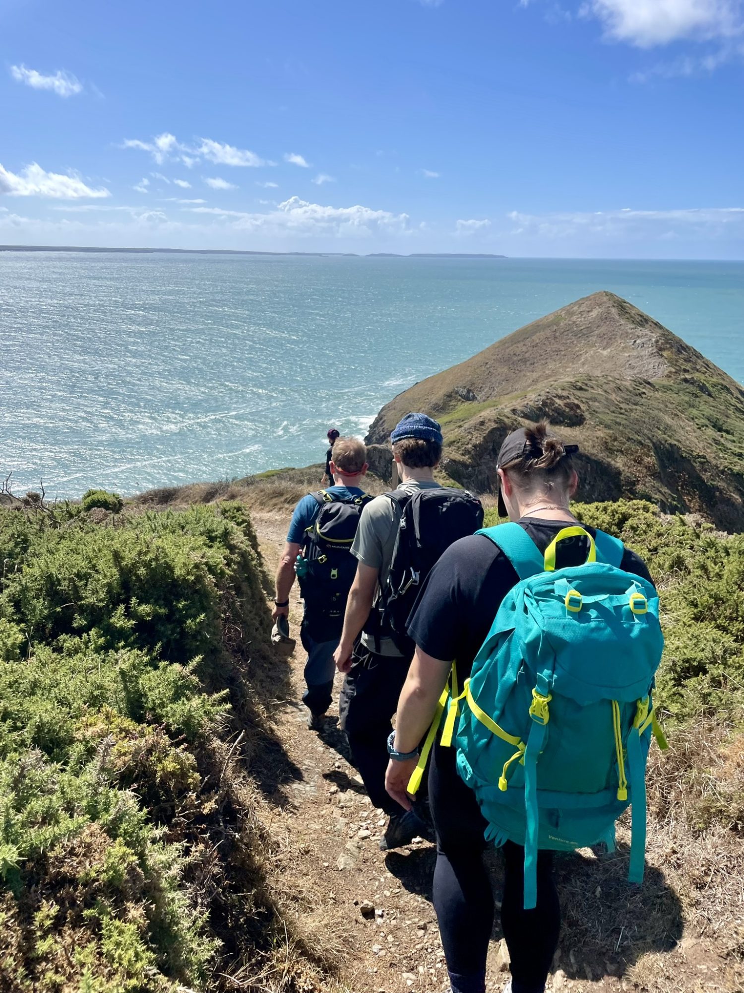 Outdoor instructor training students hill walking along a coastal path during a guided training journey
